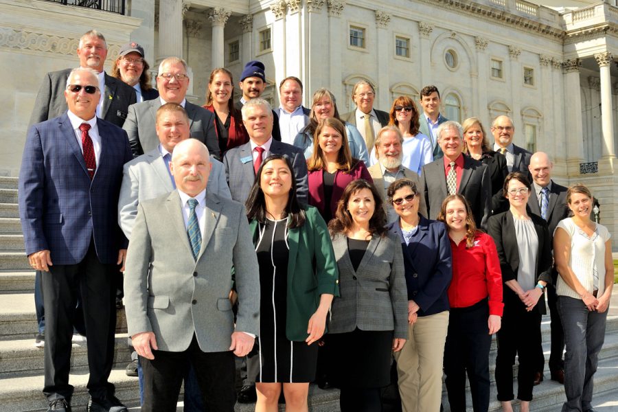 large group of people posing in front of government building