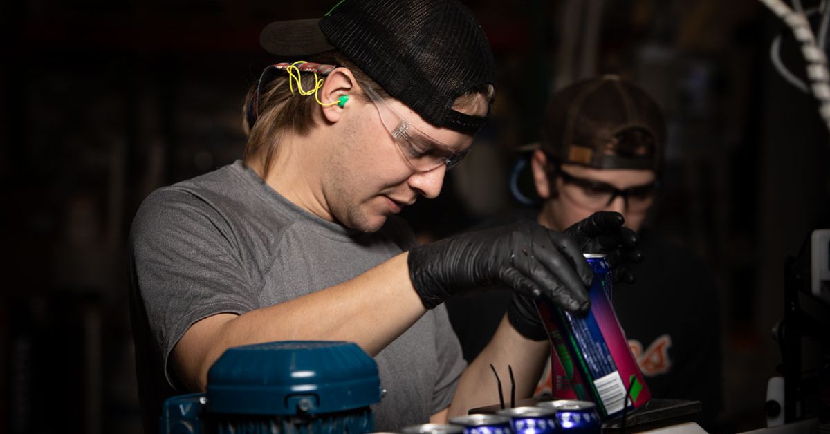 man working canning line wearing ear and eye protection